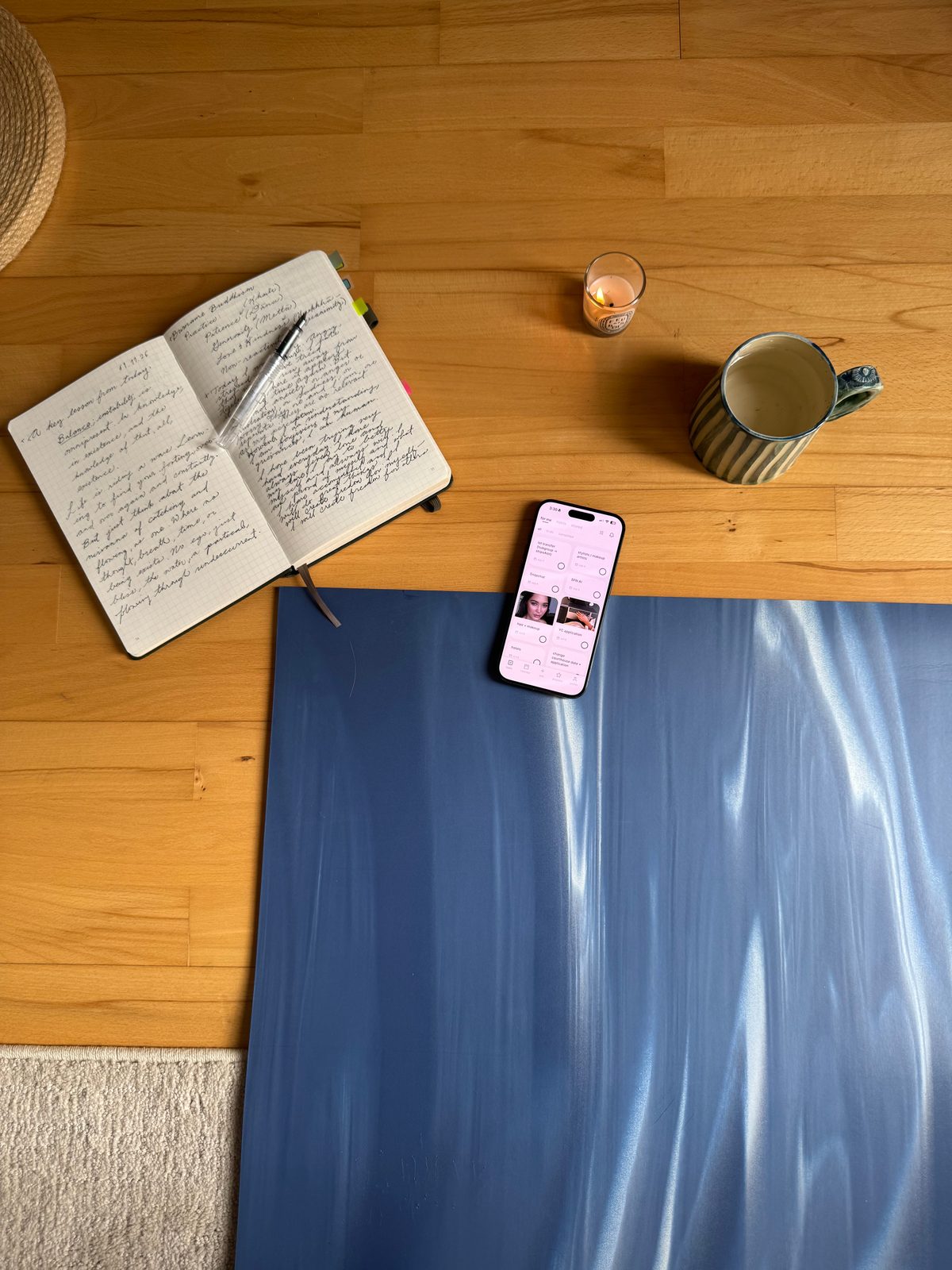 a phone with clennd open resting on a yoga mat beside a notebook and a mug