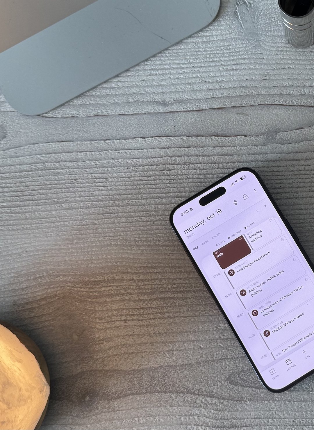 a phone showing the clennd calendar on a pale wooden desk